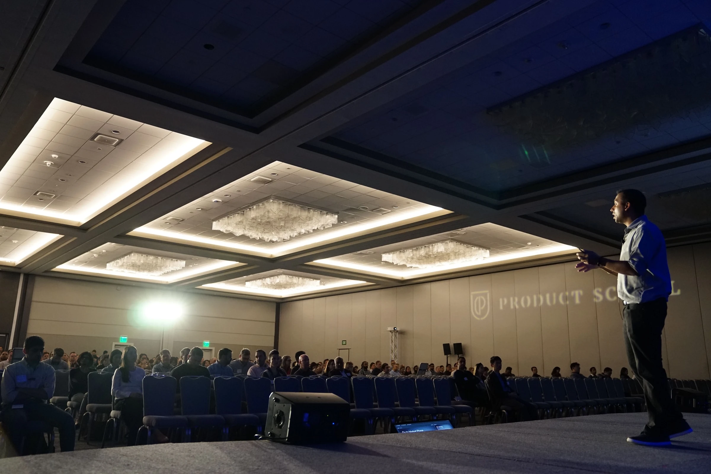 man talking in front of big crowd in a stage